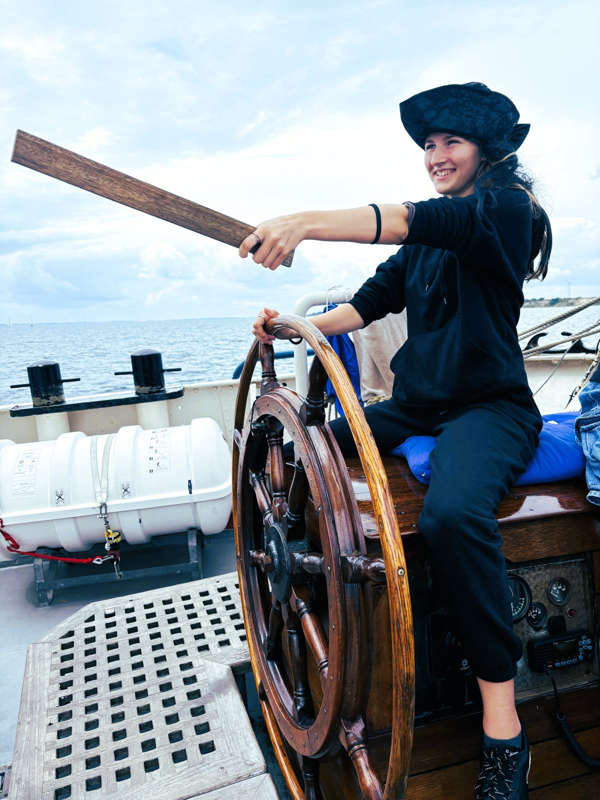 Teen girl having a laugh as a pirate at the helm